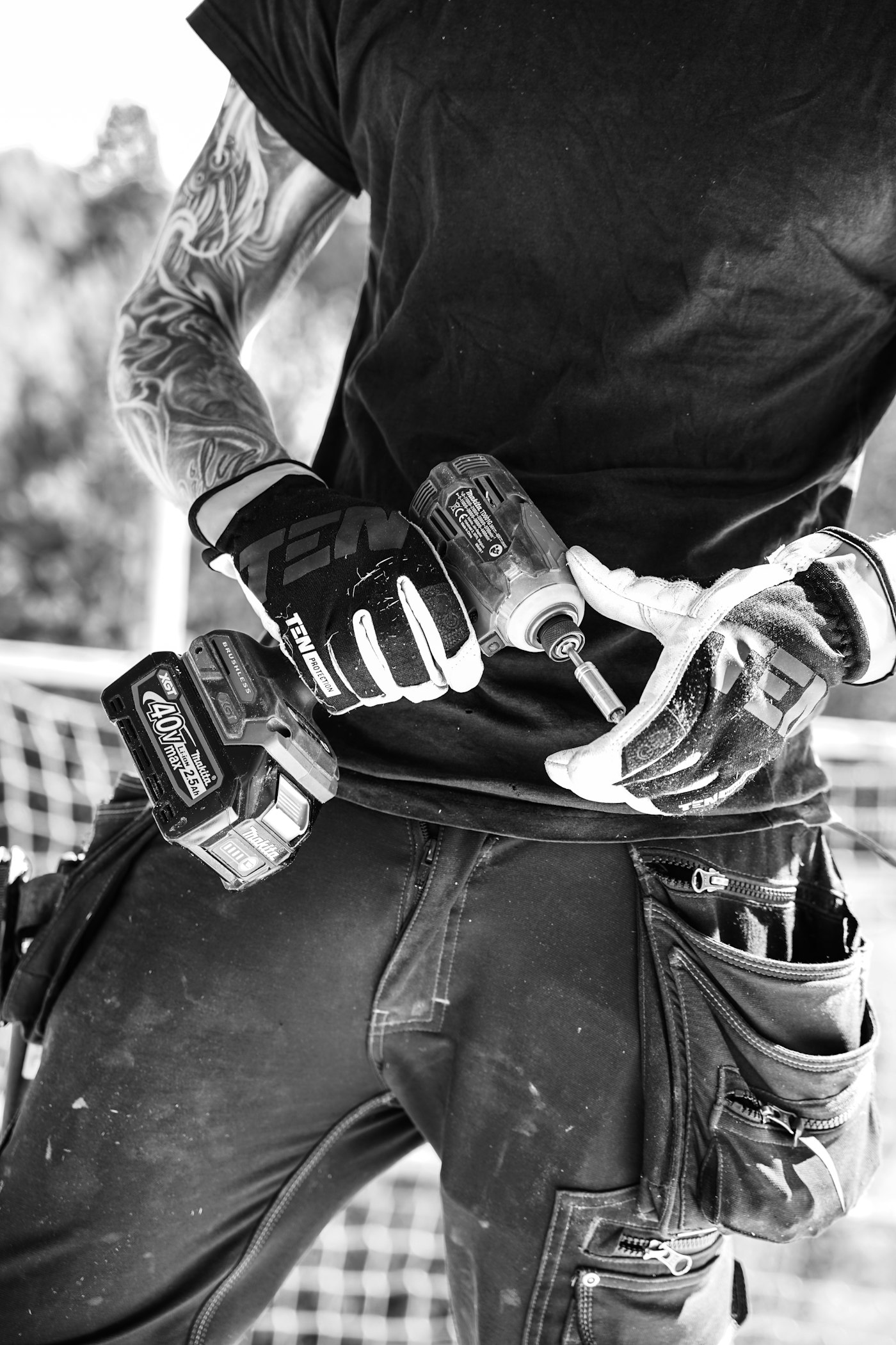 Handyman in work gloves with an impact driver and tool belt